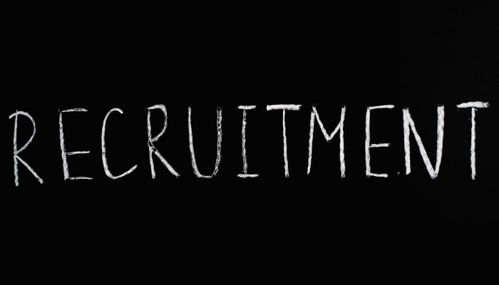 Chalk-written 'RECRUITMENT' on a black chalkboard, ideal for HR and hiring themes.