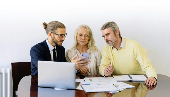 Three individuals collaborating on financial documents during a business meeting.